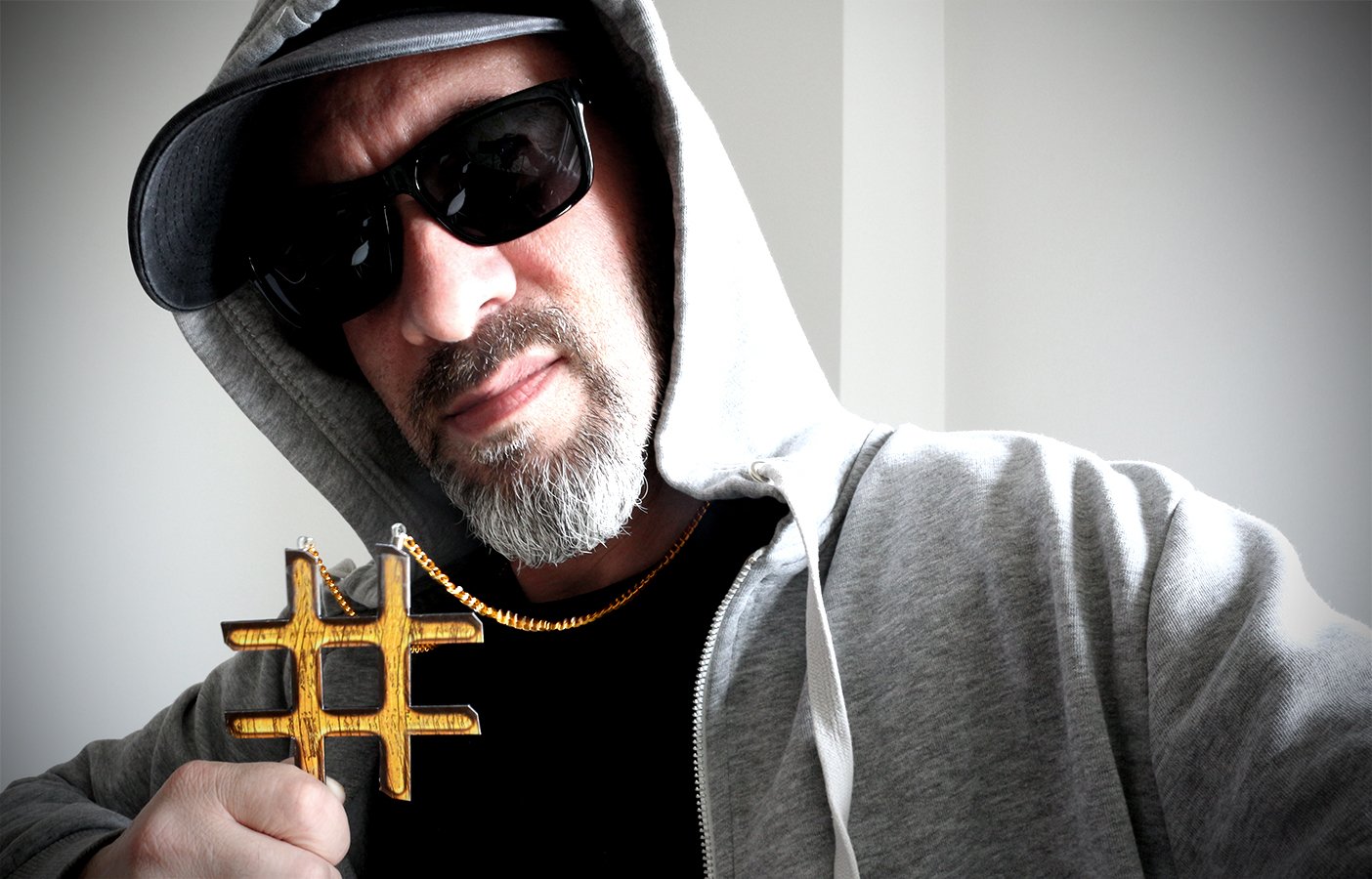 Mann mit Kapuze, Sonnenbrille und Hashtag-Kette