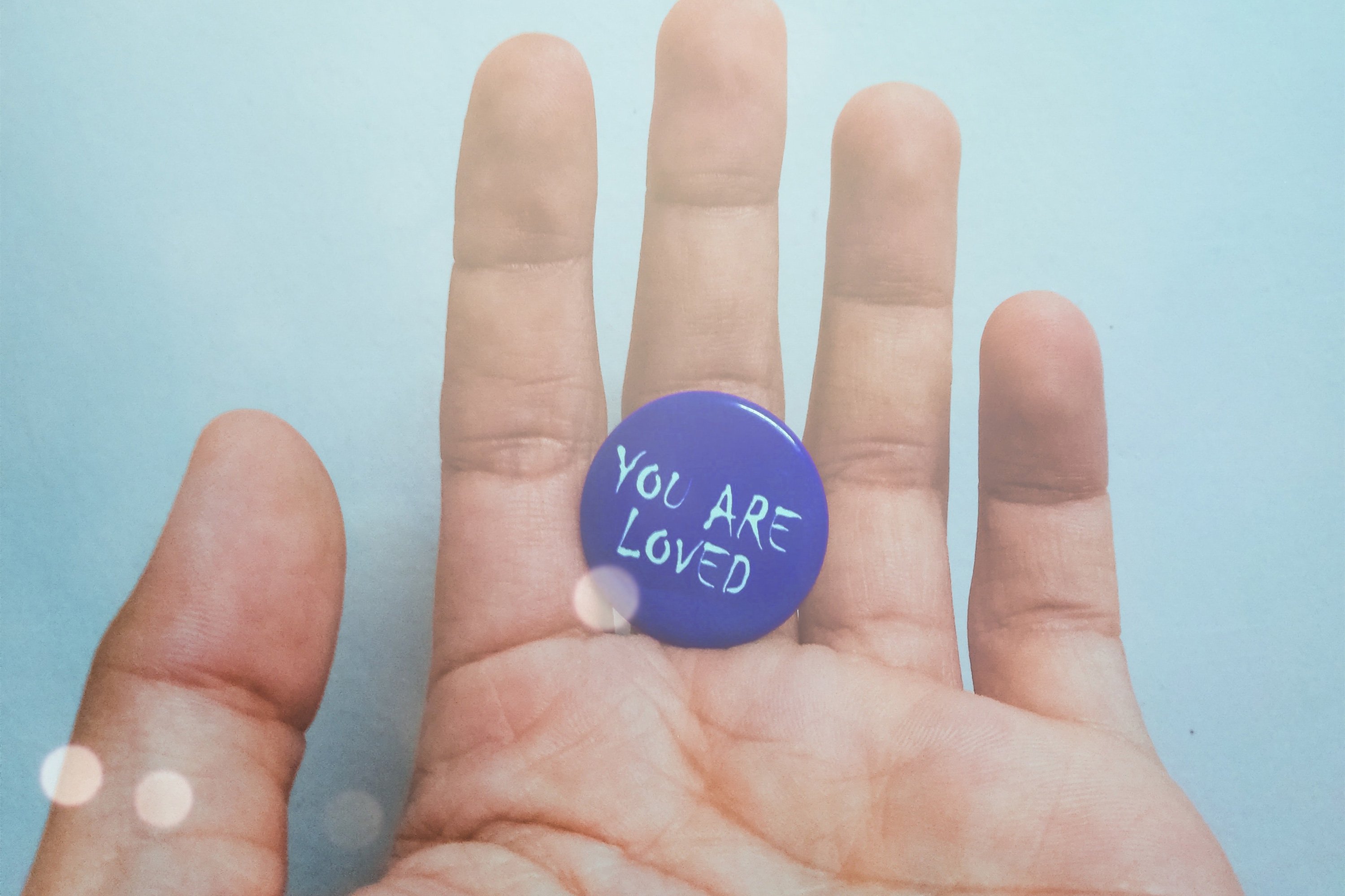 Hand mit lila Button "You are loved"