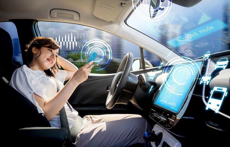 Autonomes Fahren Autocockpit mit Bildschirm und junge Frau schaut auf Smartphone